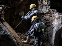 Two workers with helmet and protective suit using drill-machines in an underground enviroment