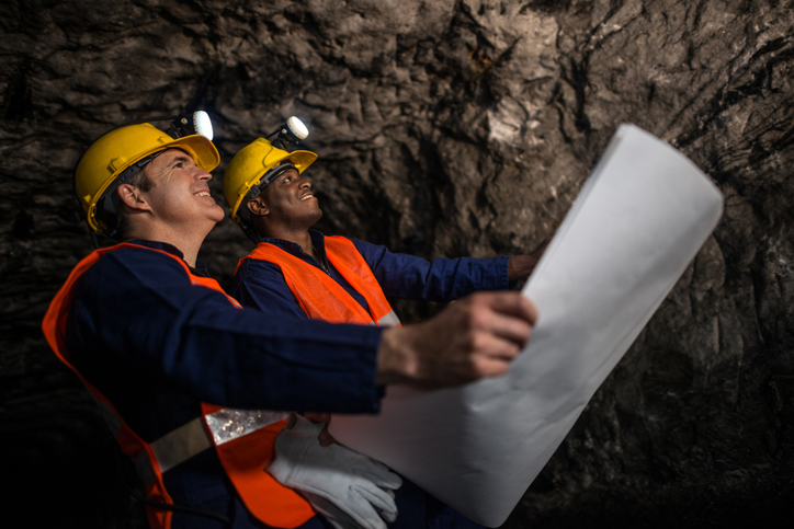 Miners working at the mine underground holding a blueprint - mining
