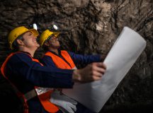 Miners working at the mine underground holding a blueprint - mining